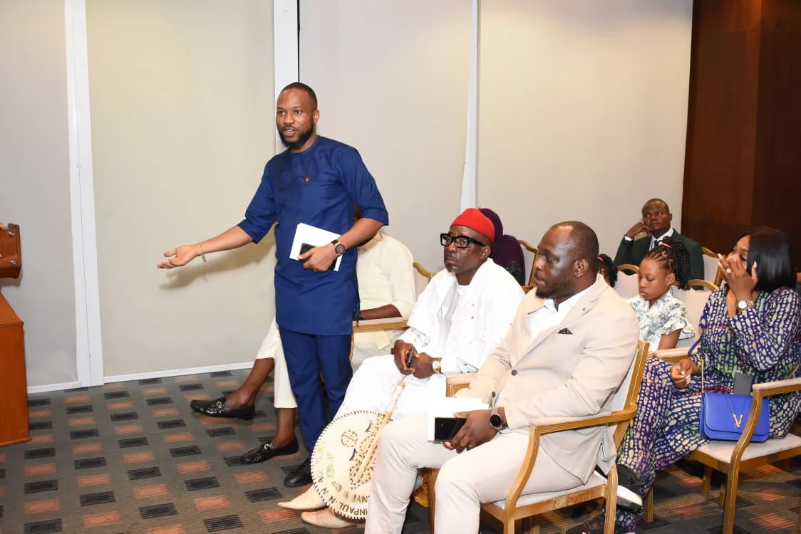 Community representative in blue addressing guests from the floor