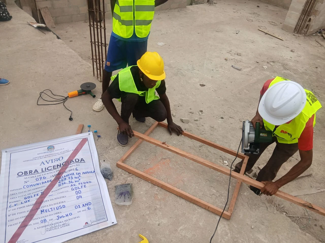 Workers measuring and cutting timber beside the construction licence at the Golf 11 site